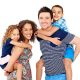 Portrait of playful young parents giving piggyback ride to children on white background